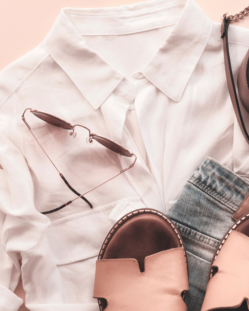 White shirt, sunglasses, and sandals on a light pink background